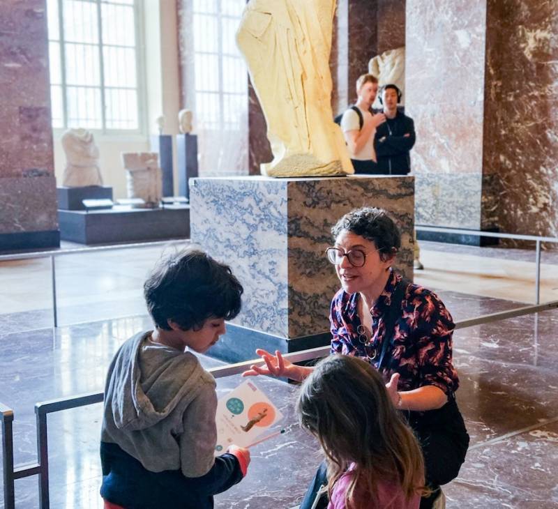 Private Guide explaining Venus de Milo for kids with their small museum notebooks