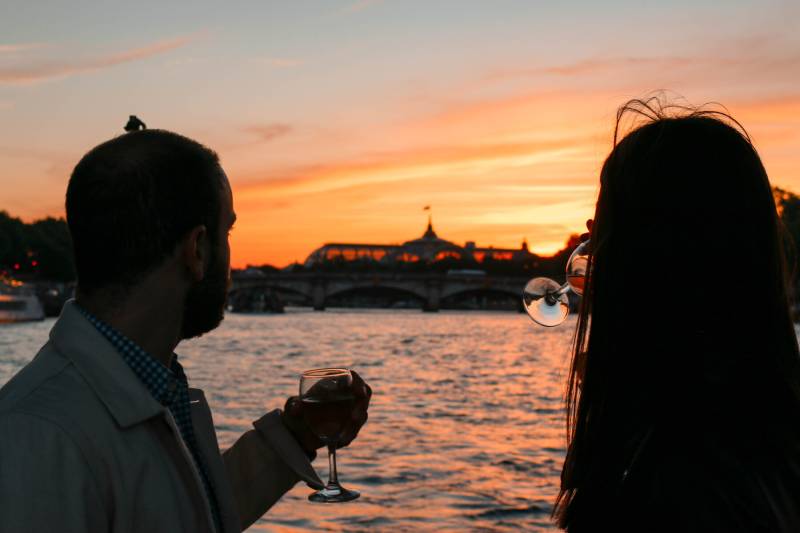 Couple enjoying wine and watching the sunset from a pontoon river boat cruise in Paris