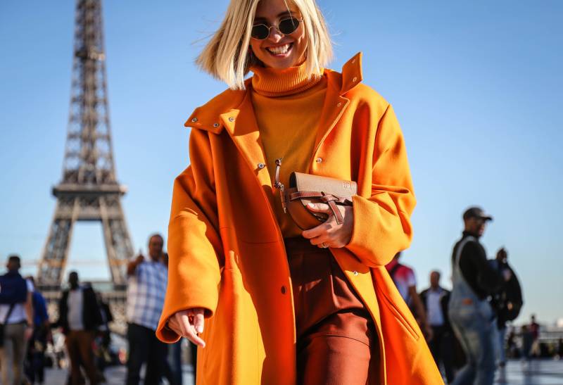 Classy stylish woman with orange clothes and Eiffel tower behind