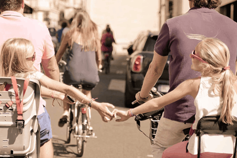 kids behind two adults biking in Paris